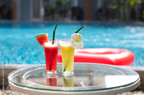 Two Colorful Tropical Cocktails on table neer swimming pool. Pineapple and watermelon smoothie. photo