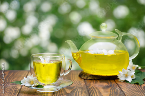 glass cup and teapot of green tea with jasmine flowers