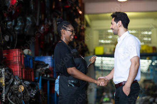 African American female employee worker and hispanic man manager working together at old auto and car parts warehouse store.