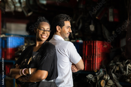 African American female worker and man customer choose and inspecting car part products while working in a old car part warehouse store.