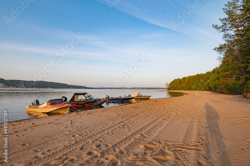Morning landscape, sunrise over the river, sandy beach near the shore are boats.