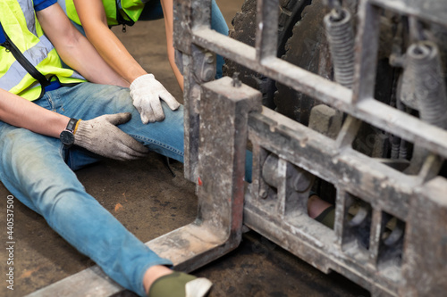 injured Asian man worker after accident in a old car parts warehouse. Forklift crash leg worker accident