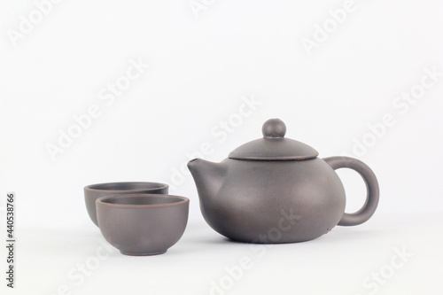 A Chinese black ceramic teapot and teacup isolated on a white background.