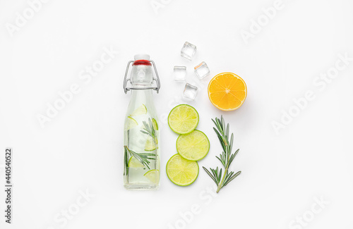 Composition with bottle of healthy lemonade and citrus fruits on white background