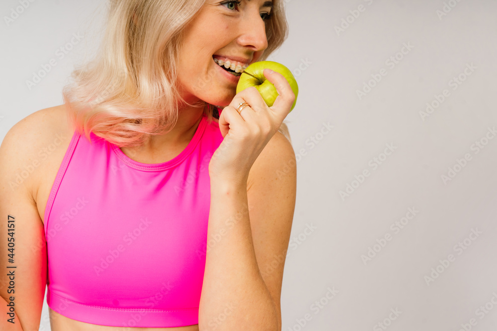 Studio shot of young fitness woman in sports clothing holding green apple, fruits, vegetables. Studio shot of young fitness woman in sports clothing holding green apple, fruits, vegetables.