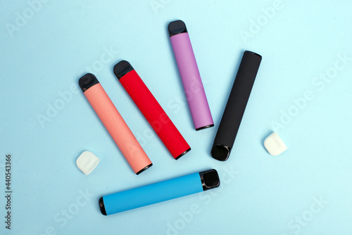 Layout of colorful disposable electronic cigarettes on a blue background. The concept of modern smoking, vaping and nicotine. Top view