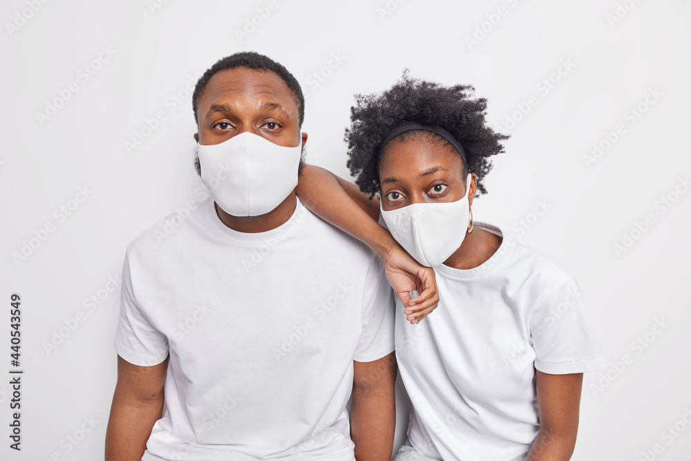 Two black Afro American woman and man wear protective face masks during covid 19 pandemic dressed in casual t shirts isolated over white background. Safety virus protection and epidemic concept