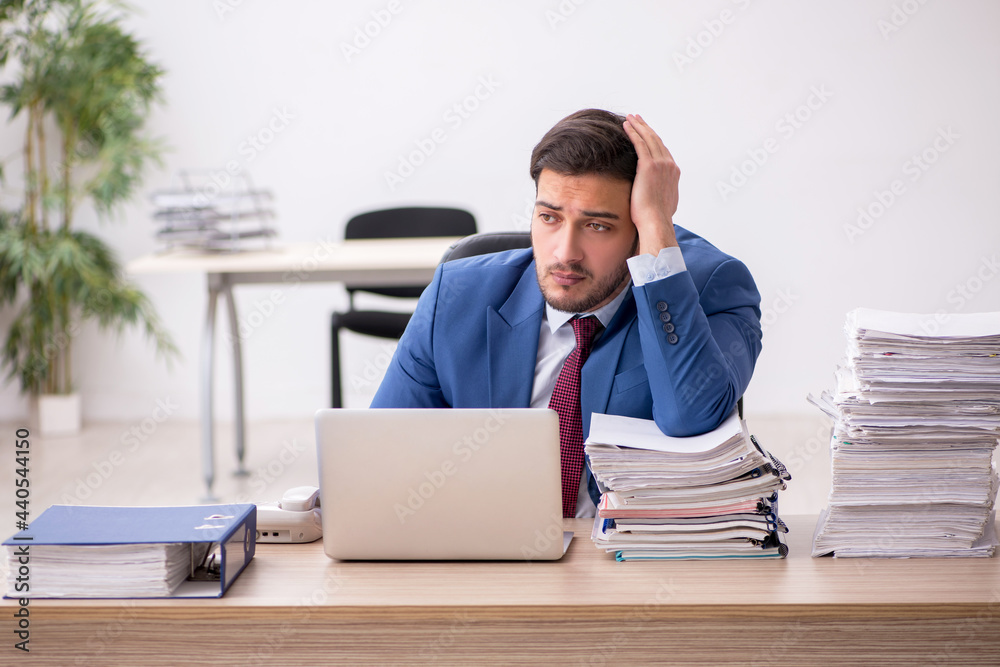 Young male employee and too much work in the office Young male employee and too much work in the office