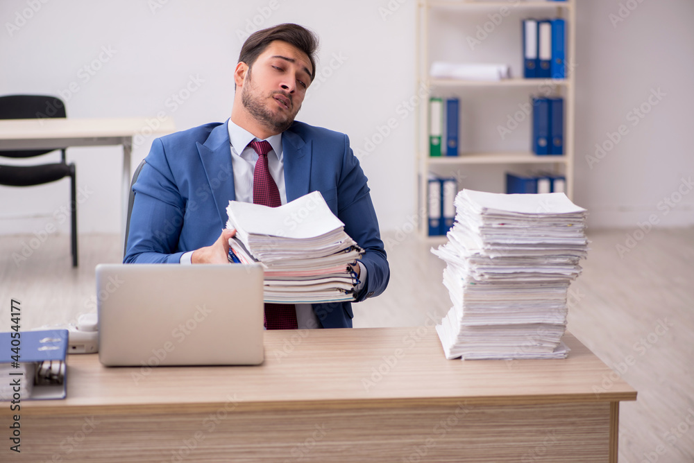 Young male employee and too much work in the office Young male employee and too much work in the office