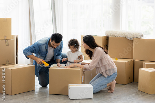 The family just bought new furniture and helped organize the house. Mon dad and daughter just moving new home. They unpacking parcel box and arranging on the floor in the living room. © Nopphon