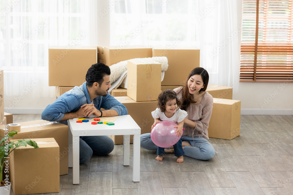 Parents and daughters play with pink balloon sitting on the floor in the living room at home. The family just moved to a new house. Happy moment Multi-ethnic dad mom and child. Parents and daughters play with pink balloon sitting on the floor in the living room at home. The family just moved to a new house. Happy moment Multi-ethnic dad mom and child.