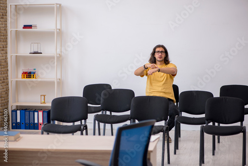 Young male student waiting for teacher in the classroom