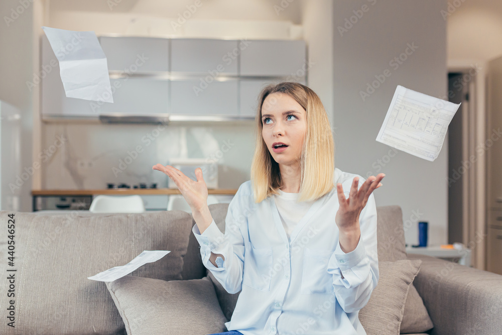 Worried housewife pays inflated bills while sitting on sofa at home, frustrated with work, and monthly income Worried housewife pays inflated bills while sitting on sofa at home, frustrated with work, and monthly income
