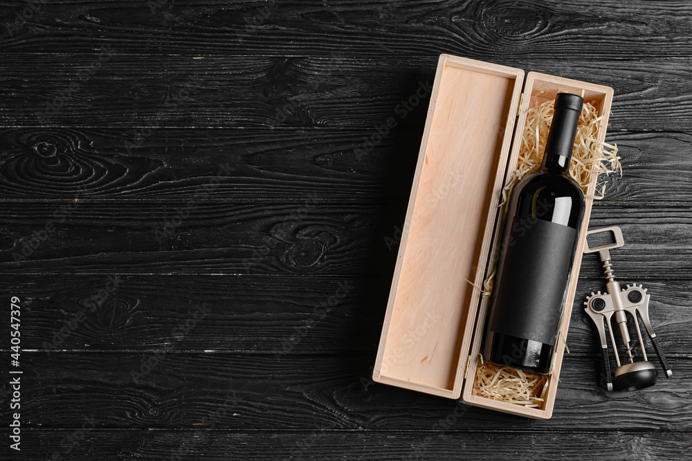 Box with bottle of wine and corkscrew on dark wooden background - obrazy, fototapety, plakaty 