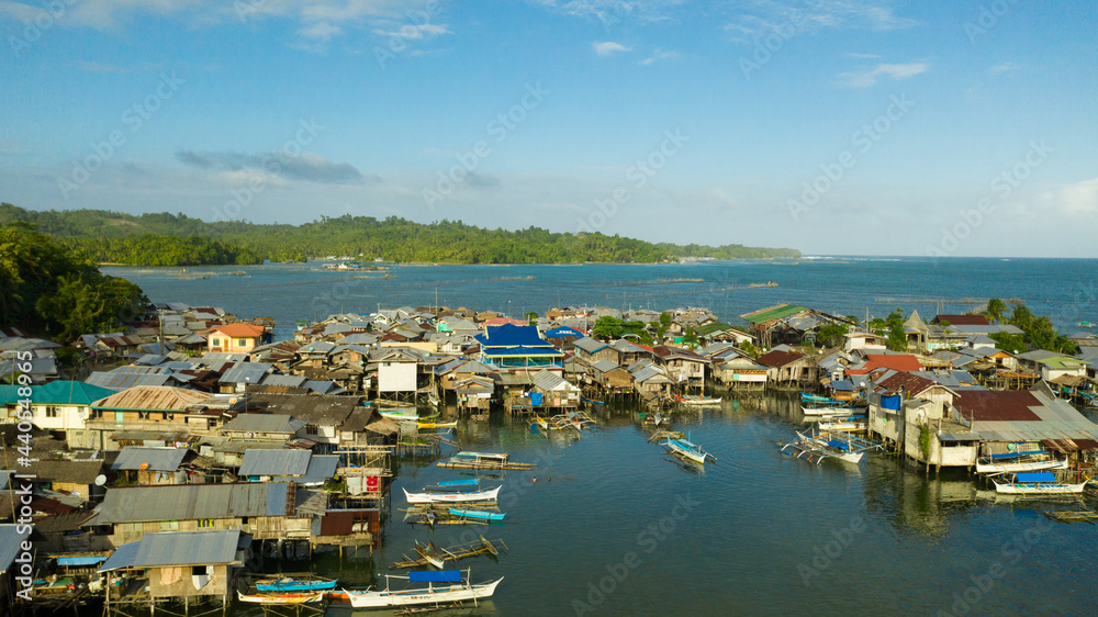Fishing village with wooden houses on stilts in the sea. Village of fishermen with houses on the water, with fishing boats. Philippines, Mindanao.
