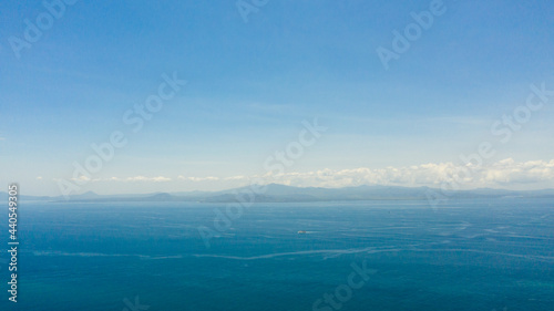 Blue sea and the tropical island of Basilan with mountains. Seascape with a tropical island. Zamboanga, Mindanao, Philippines.