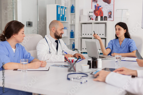 Medical nurse discussing disease examination with research team sitting in clinical meeting room. Professional physicians doctors prescribing pills medication treatment against sickness