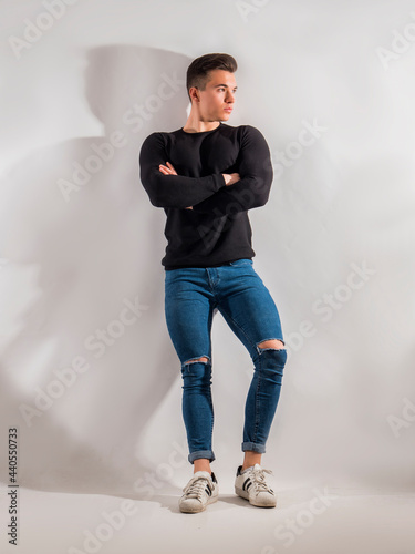 One handsome young man in studio shot, standing confindent with arms crossed photo