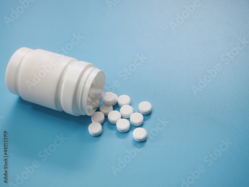 White pharmaceutical medicine pills and bottle on a blue background. 