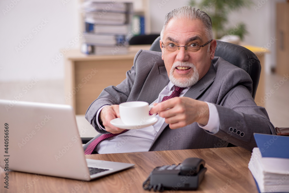 Old male employee drinking tea during break Old male employee drinking tea during break