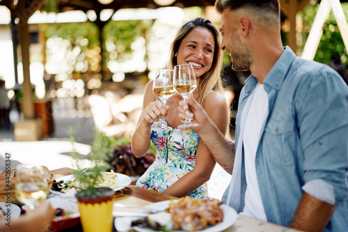 Young happy couple toasts with wine during dinner at a restaurant during a summer day
