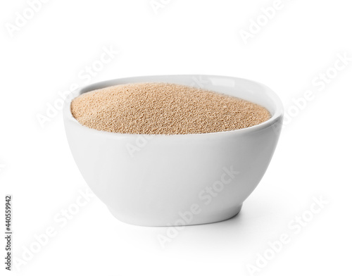 Bowl with active dry yeast on white background