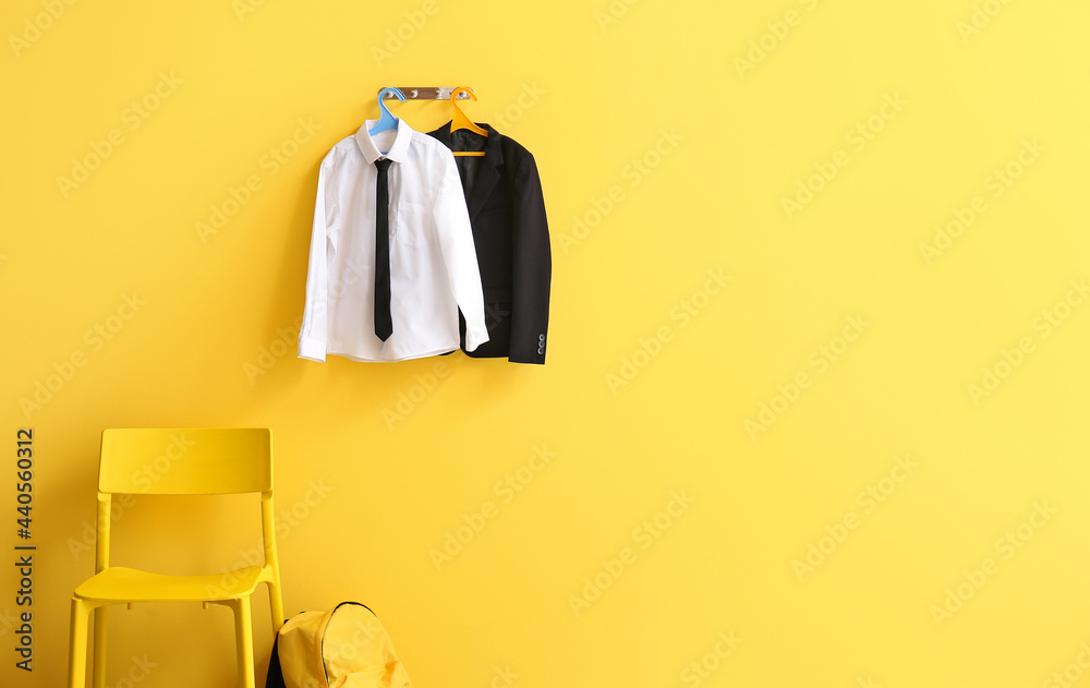 Hanger with stylish school uniform on color wall in room - obrazy, fototapety, plakaty 