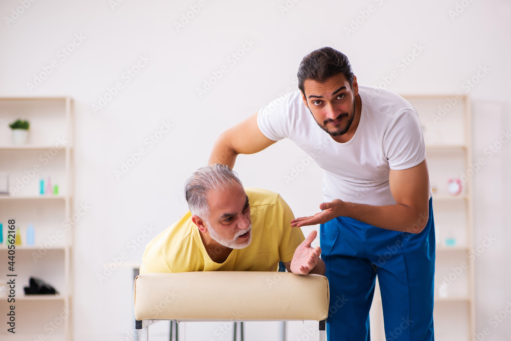 Fototapeta premium Old male patient visiting young male doctor chiropractor