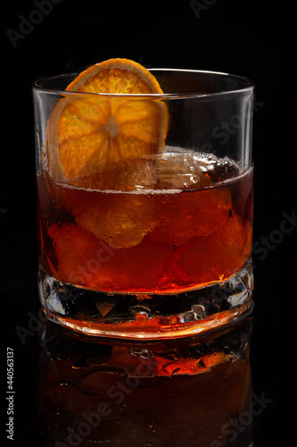 Alcoholic cocktail Old fashioned cocktail with orange slice and lump sugar on black background. Copyspace