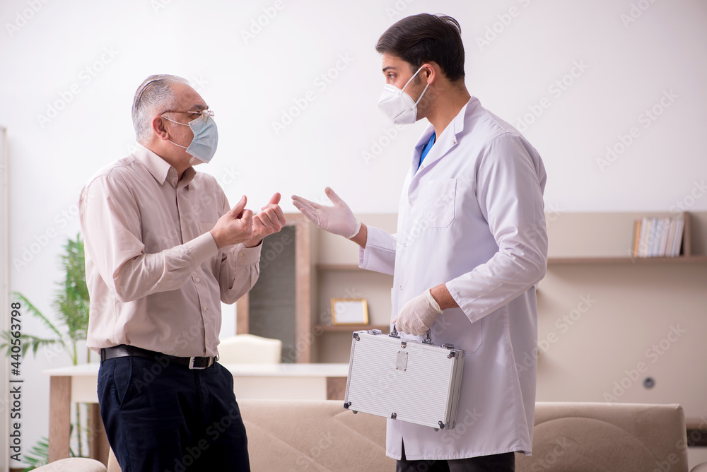 Fototapeta premium Young male doctor visiting old patient in vaccination concept