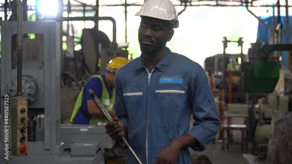 portrait of african american heavy industry worker wearing hard hat and yellow ear muffs standing confident holding wrench tools in Large Industrial Factory. young black engineer portrait of african american heavy industry worker wearing hard hat and yellow ear muffs standing confident holding wrench tools in Large Industrial Factory. young black engineer