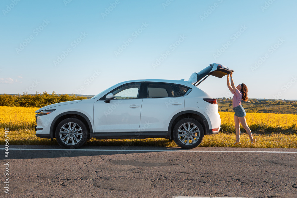 woman closing car trunk parked at roadside woman closing car trunk parked at roadside