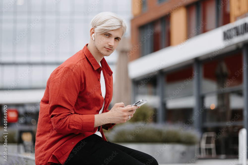Smart confident teenager with his phone outside. Portrait of blonde young hipster with his phone. Smart confident teenager with his phone outside. Portrait of blonde young hipster with his phone.