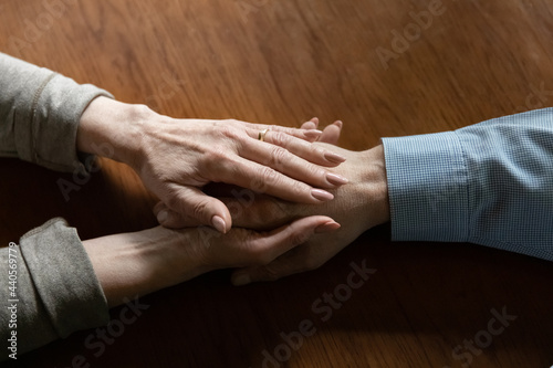 Crop close up of mature woman hold old husband hand show love and care in relationships. Attentive middle-aged wife comfort caress support senior man spouse, feel supportive. Family unity concept.