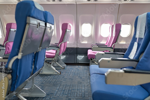 Empty passenger airplane seats in the cabin blue and pink with social distancing to prevent covid19 infection during pandemic