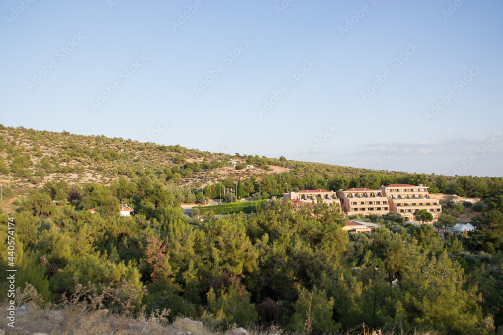 View of a hotel in a forest, nature landscape, beautiful green trees and blue sky, building in the island of Thasos