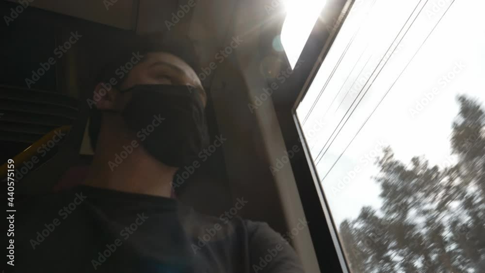 man in face mask sitting in train wagon and looking in window man in face mask sitting in train wagon and looking in window