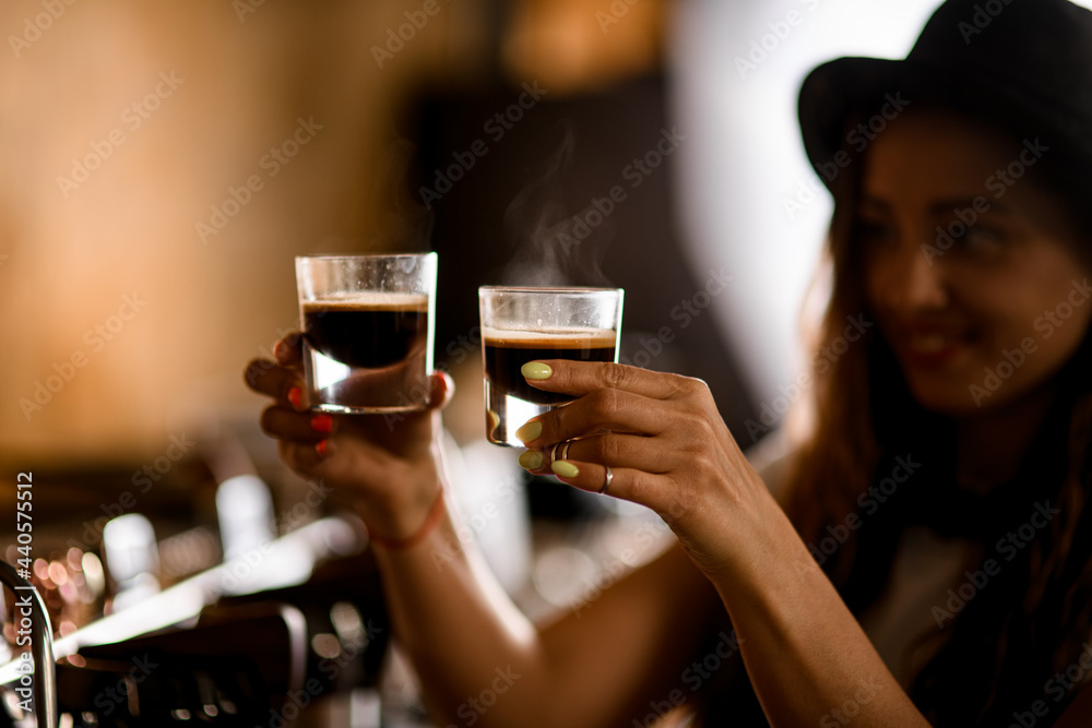two transparent glass cups with hot espresso in hands of smiling young woman barista