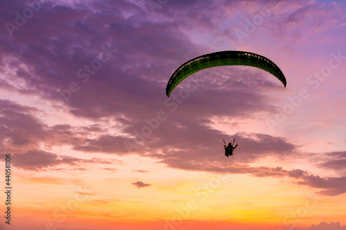 Skydiving sunset landscape of parachutist flying in soft focus. Para-motor flying silhouette with sun set. Silhouette of paraglider flying in the evening sky with sunset.