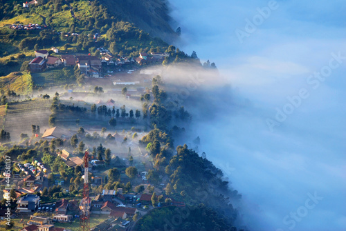 Landscape natural scene of Little village with many fog and Misty around mountain and village with shining sunrise at cemero lawang of Bromo Mountain , Indonesia - Morning vibe greenery travel unseen photo