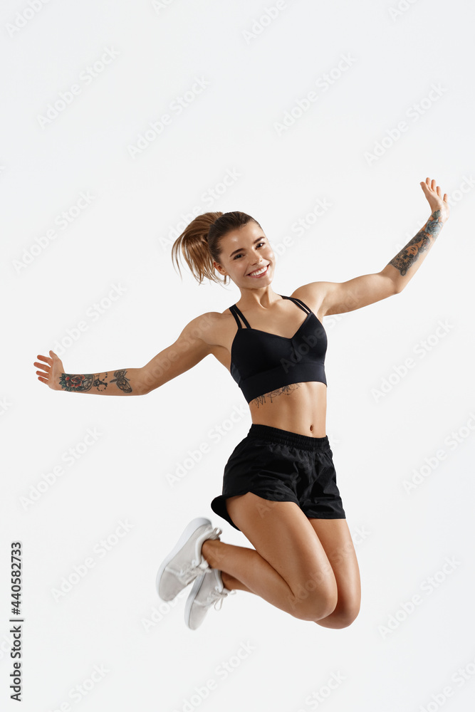 Jump. Dynamic movement, sillhouette of sportswoman, female athlete jumping in sportswear and smiling happy at camera, workout and gym advertising, isolated on white background