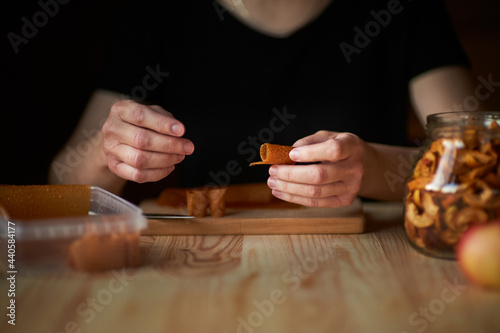 Females hands are rolling up the apple fruit leather. The best way to store the fruit leather is to cut them into strips and roll them up in parchment paper. Dehydrated Apples for Food Storage. photo