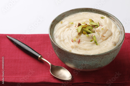 Shrikhand is an Indian sweet dish made of strained curd, garnished with dry fruits and saffron. Served in a ceramic bowl.
 photo