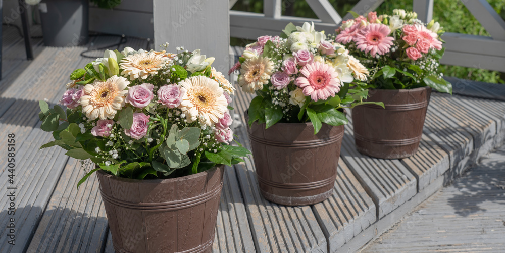 Three brown flower pots with bouquets of flowers. Three brown flower pots with bouquets of flowers.