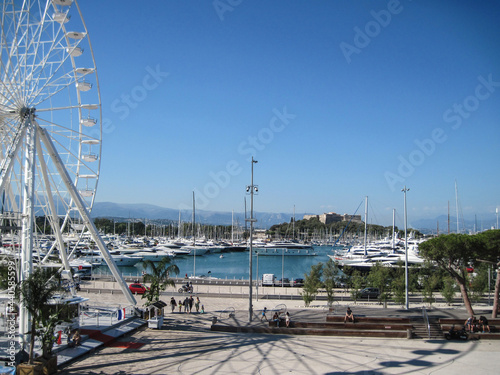 Scenic panoramic seaside view with old castle Antibes and many large yachts on a sunny day. People enjoying life in the summer sail on a yacht. Wonderful travel vacation with swimming in Azure Coast.