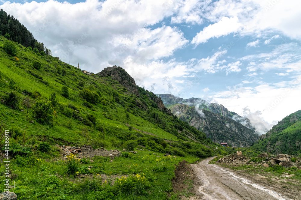 Mountain road and storm clouds over alpine meadows Mountain road and storm clouds over alpine meadows