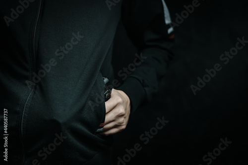 Guy is threatening with gun in his jacket pocket. Night thief and robber. Criminal hides weapon in clothes. © Konstantin Savusia