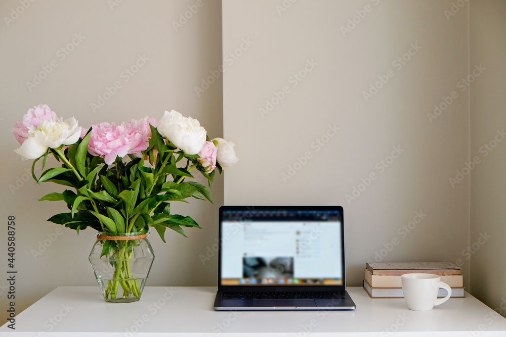 Home office concept. Designated work from home area near the window. Modern laptop, notebook and vase with flowers on table. Close up, copy space, background. Home office concept. Designated work from home area near the window. Modern laptop, notebook and vase with flowers on table. Close up, copy space, background.