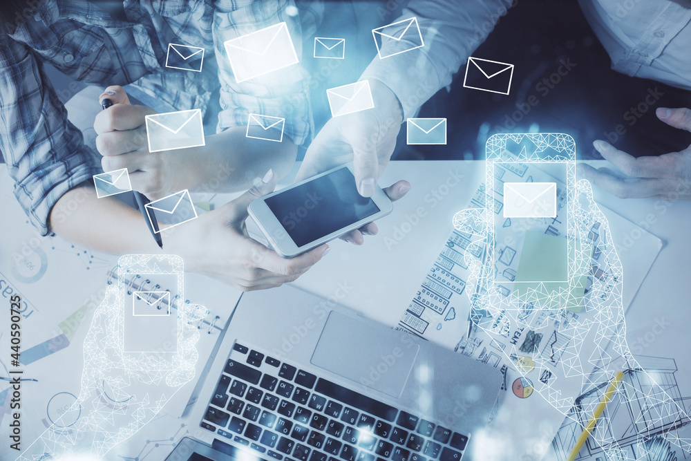 Double exposure of envelop theme hologram and man and woman working together holding and using a mobile device. Double exposure of envelop theme hologram and man and woman working together holding and using a mobile device.