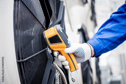 Technician uses a thermal imaging infrared thermometer to check the condensing unit heat exchanger.